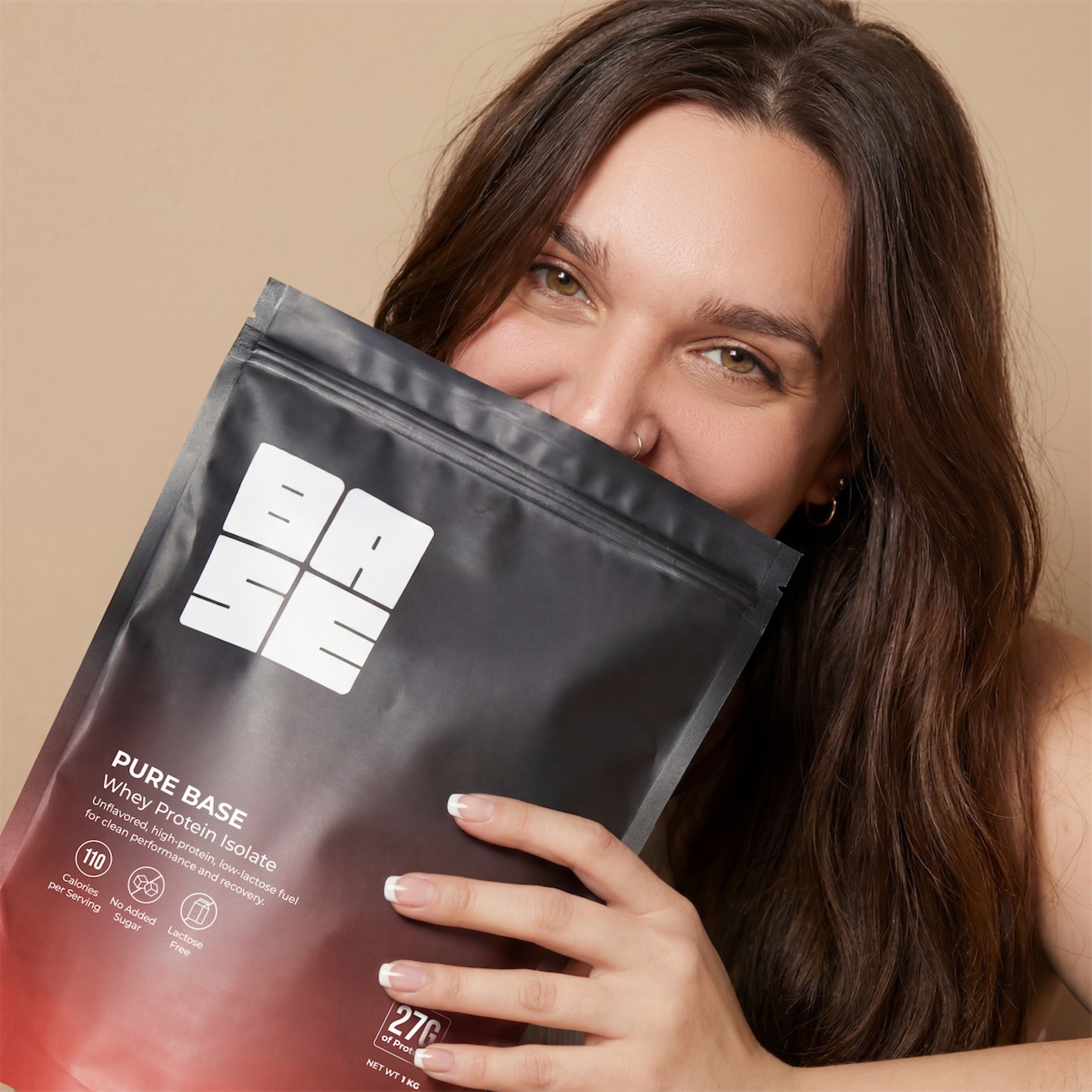Woman holding a protein powder package with a neutral background