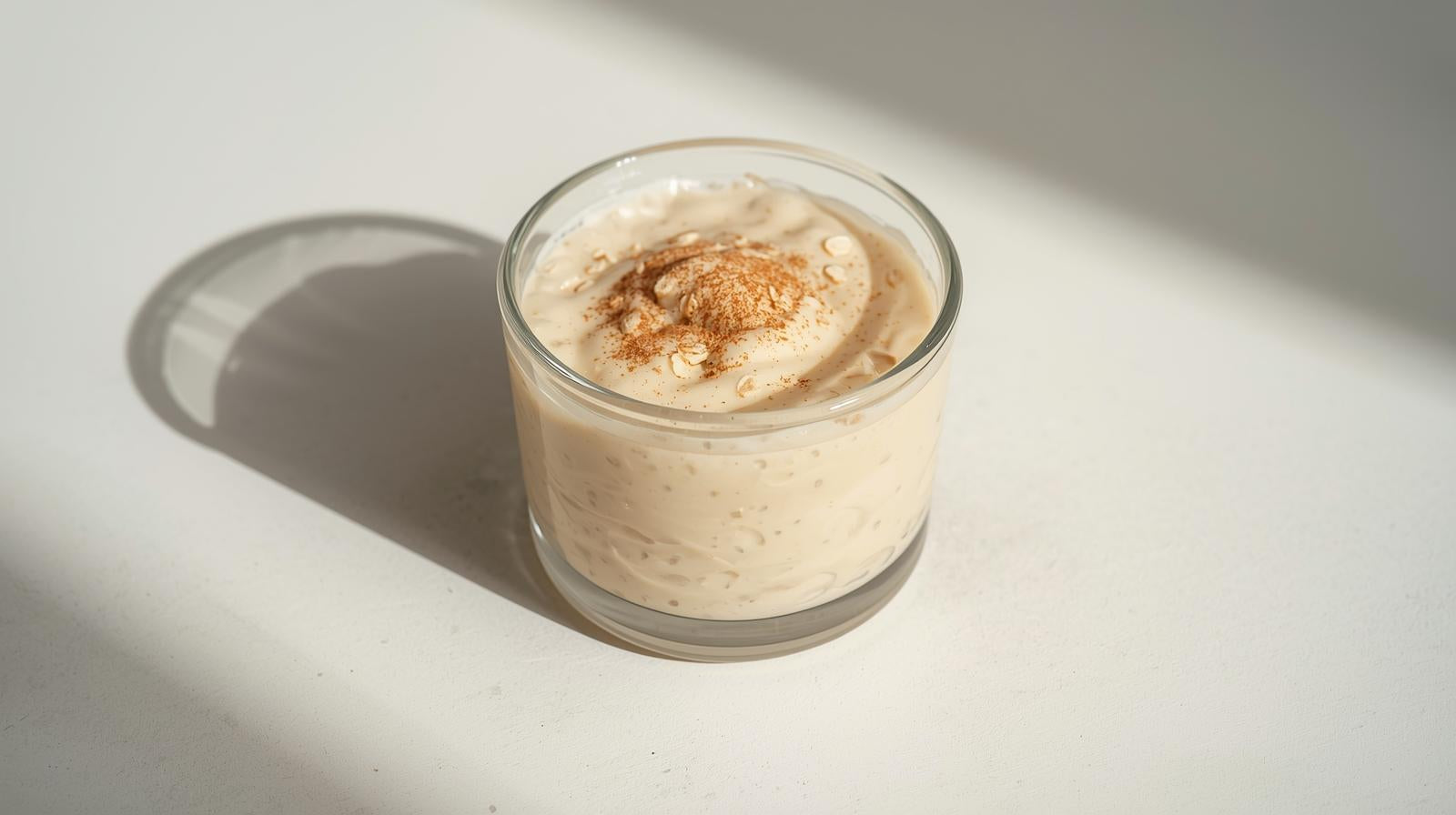 Glass container with creamy dessert on a light background