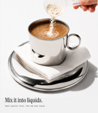 A silver metal cup filled with coffee sits on a white napkin and silver saucer, with a hand pouring a fine beige powder into the cup. Text at the bottom reads, 'Mix it into liquids.